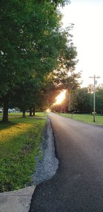 Empty road by trees against sky