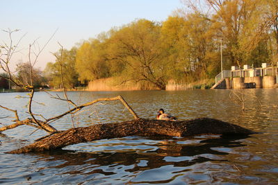 Man by lake against sky