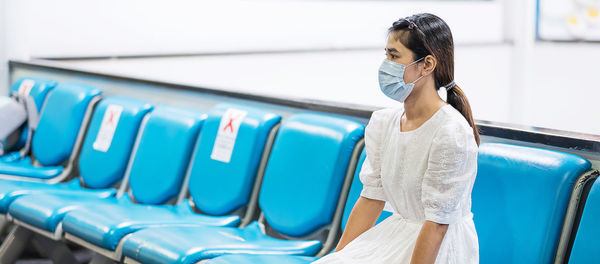Woman wearing mask sitting at airport
