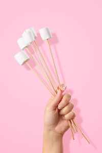 Close-up of hand holding plastic against colored background