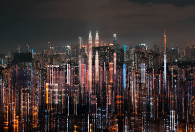 Illuminated modern buildings in city skyline against the night sky