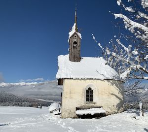 Church by building against sky during winter