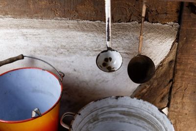 High angle view of ladles and buckets by wooden wall