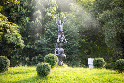 Statues on field against trees