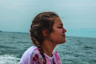 Close-up of young woman at beach against sky