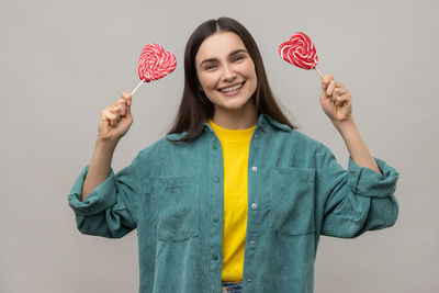 Portrait of young woman holding gift against wall