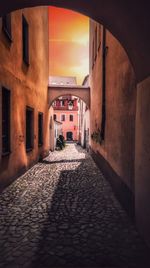 Alley amidst buildings in town at sunset