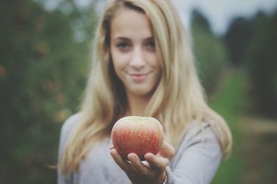 Portrait of smiling young woman holding apple