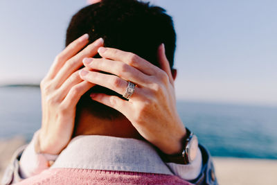Close-up of woman hand holding sea against sky