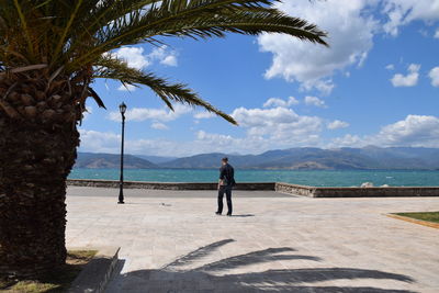 Rear view of man walking on promenade against sky