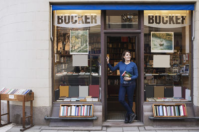 Female librarian holding book while looking away at doorway