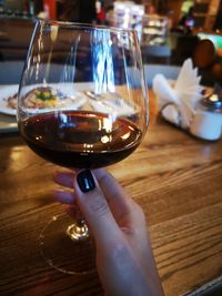 Midsection of woman holding wineglass on table