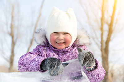 Portrait of smiling cute girl playing with ice while standing outdoors