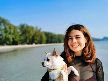 Portrait of young woman with dog against sky