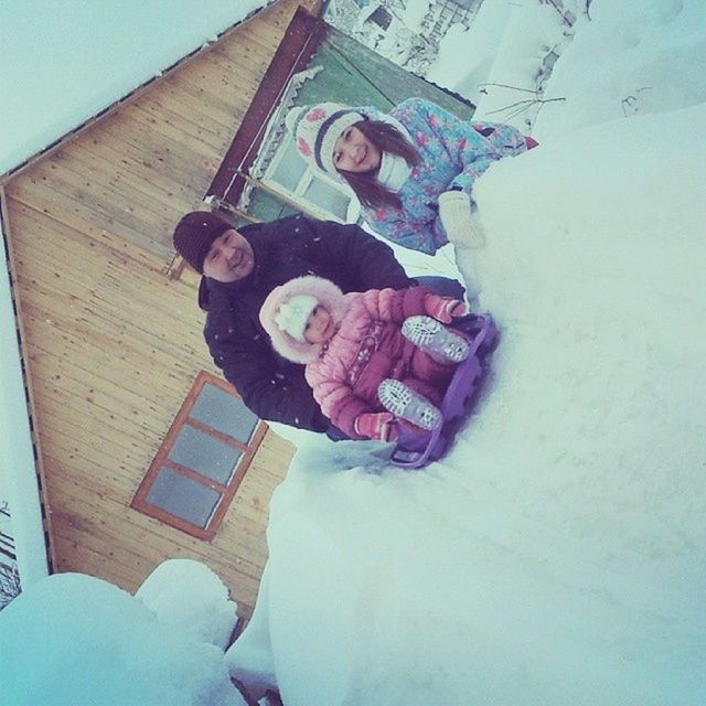 building exterior, built structure, cold temperature, architecture, winter, snow, lifestyles, childhood, leisure activity, house, day, toy, outdoors, full length, holding, warm clothing, season, high angle view