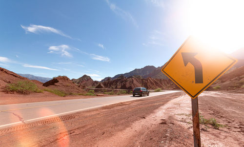 Road sign in desert against sky