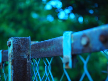 Close-up of rusty metal fence against blue sky