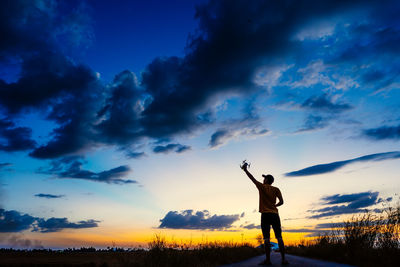 Silhouette man standing on field against sky during sunset