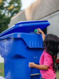Cute girl standing by garbage bin outdoors