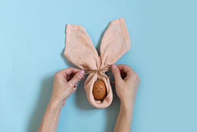 Cropped hand of woman holding gift against blue background