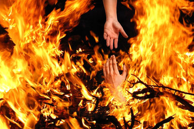 Digital composite image of hands amidst fire