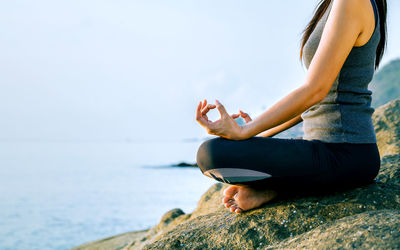 Young woman in lotus position on shore