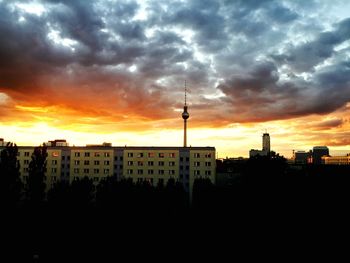Silhouette of tower against cloudy sky at sunset