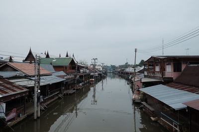 Canal amidst houses against sky in city