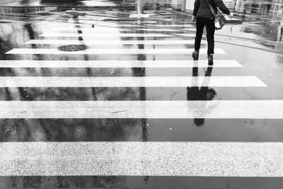 Low section of person walking on wet street in rainy season