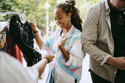 Smiling female customer looking at dress while shopping at flea market