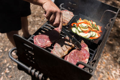 Low section of man preparing meat on barbecue grill