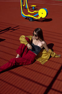 Beautiful woman wearing sunglasses relaxing on sports field