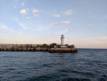 Tower by sea against sky during sunset