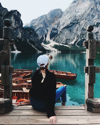 Woman sitting by lake against mountain range