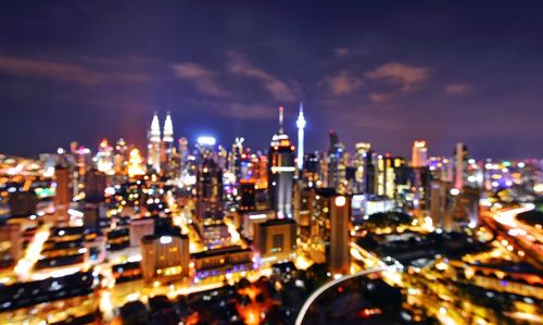 Illuminated buildings in city against sky at night