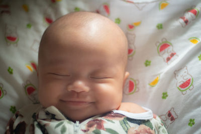 Close-up of cute baby boy lying on bed at home