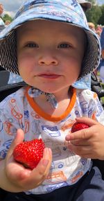 Close-up portrait of cute baby boy holding strawberries