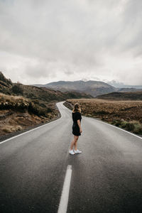 Woman standing on road against sky