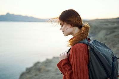 Woman looking at sea against sky during sunset