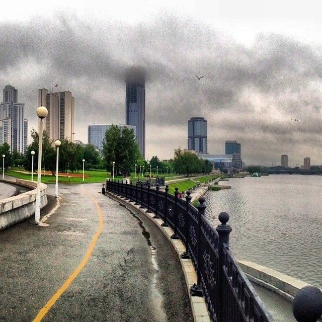 architecture, built structure, building exterior, sky, transportation, the way forward, city, road, cloud - sky, street, cloudy, water, road marking, weather, overcast, diminishing perspective, vanishing point, day, tower, car