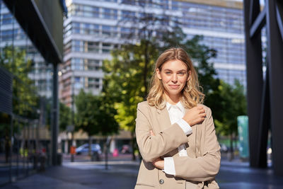 Portrait of young woman standing against building