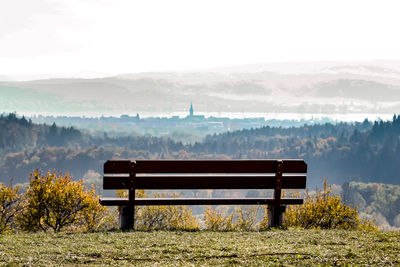 Empty bench on landscape against sky