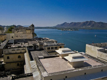 High angle view of buildings by sea against clear sky