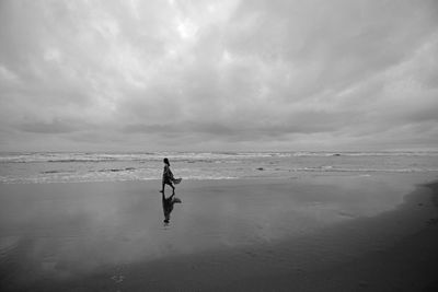 Man walking on beach against sky