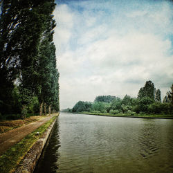 Scenic view of river against cloudy sky