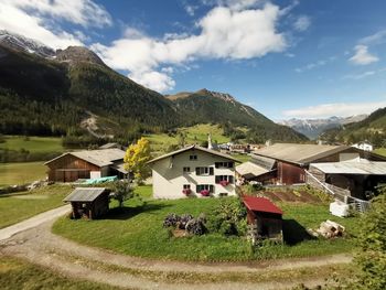 Houses on field by mountains against sky