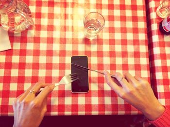 Cropped image of woman holding fork and knife on smart phone