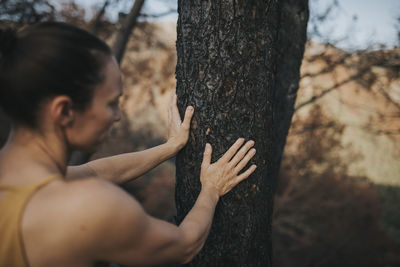 Woman touching burnt tree trunk in forest