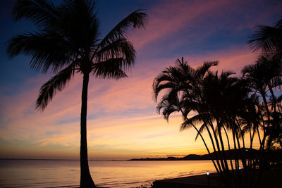 Silhouette palm tree by sea against sky at sunset