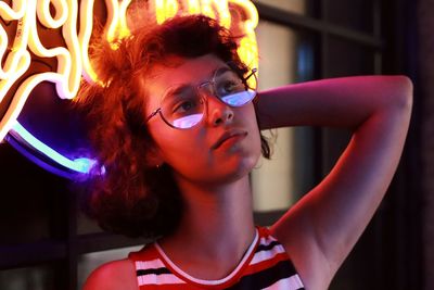 Close-up of thoughtful young woman wearing eyeglasses against window